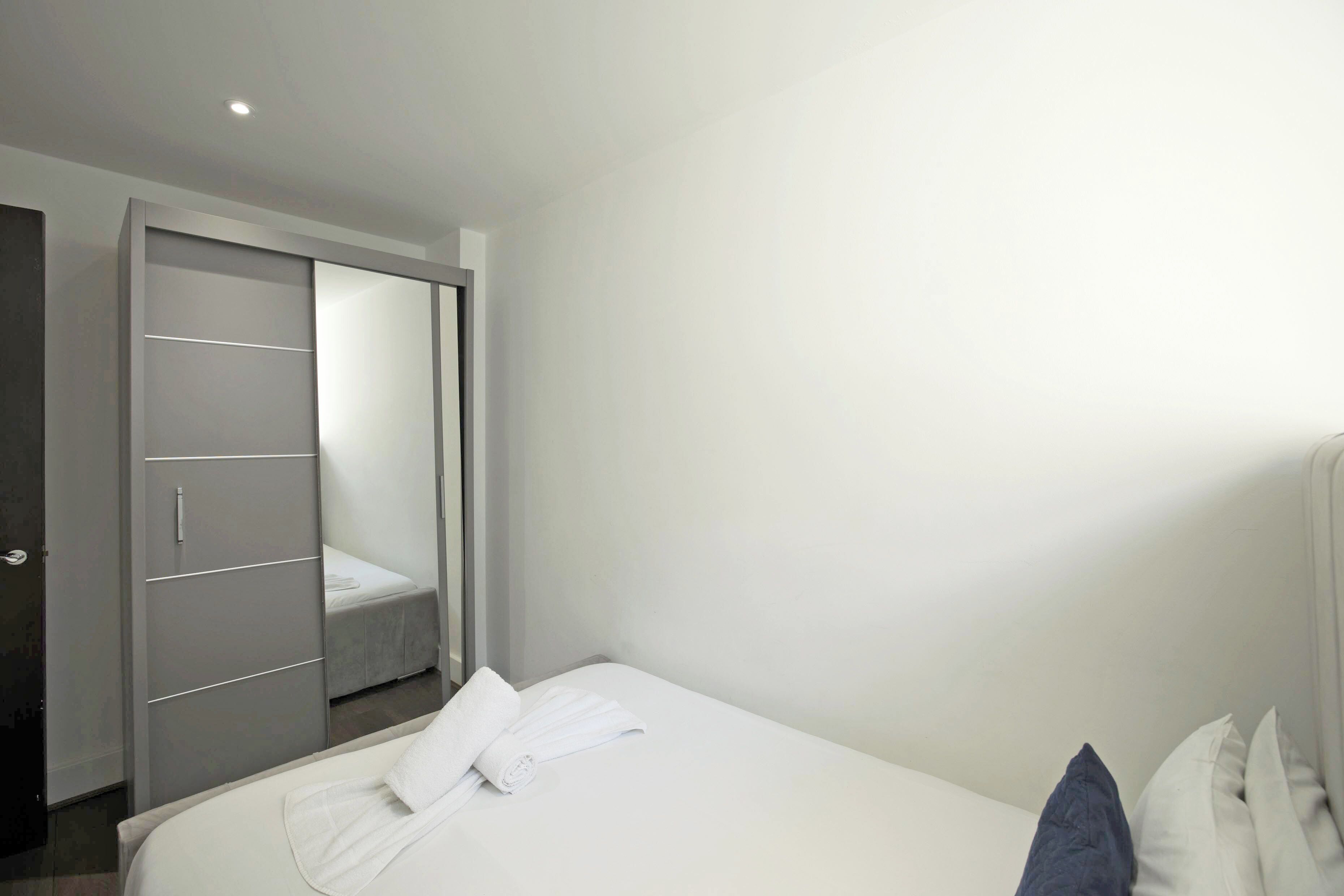 A hotel room with a bed, a wardrobe, and a door leading to a bathroom.
