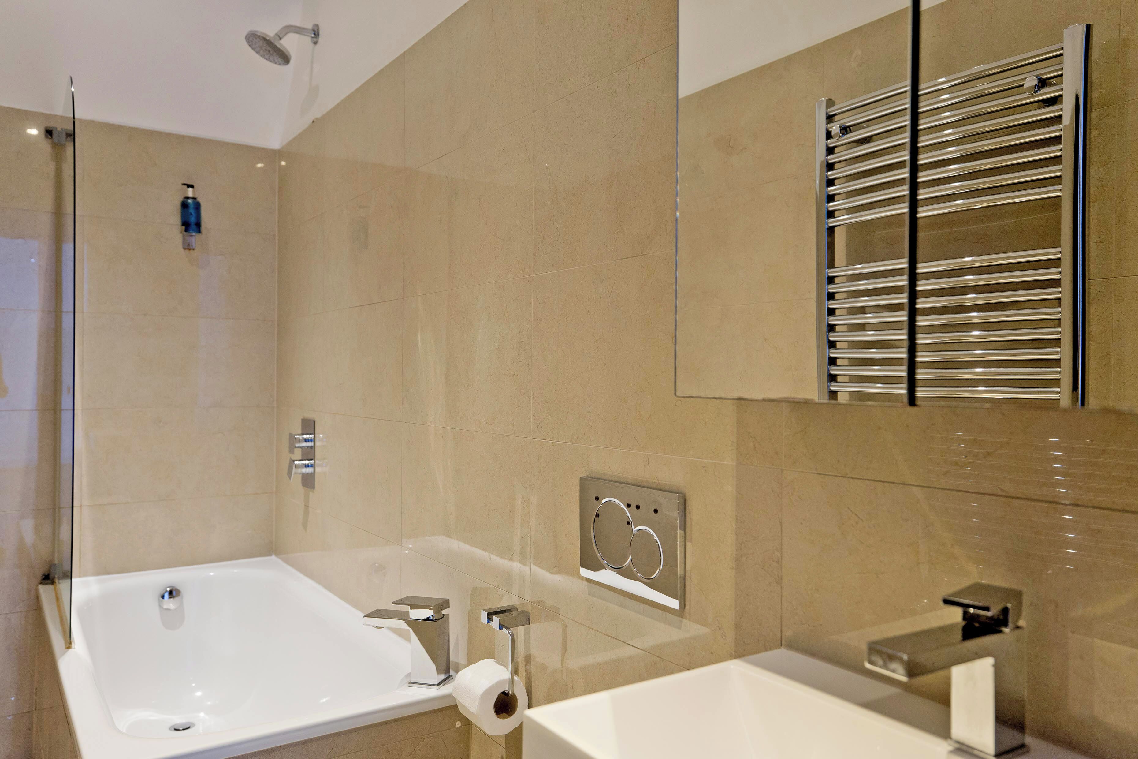 Une salle de bain moderne dotée d’une grande baignoire, d’une cabine de douche en verre et d’un porte-serviettes intégré.