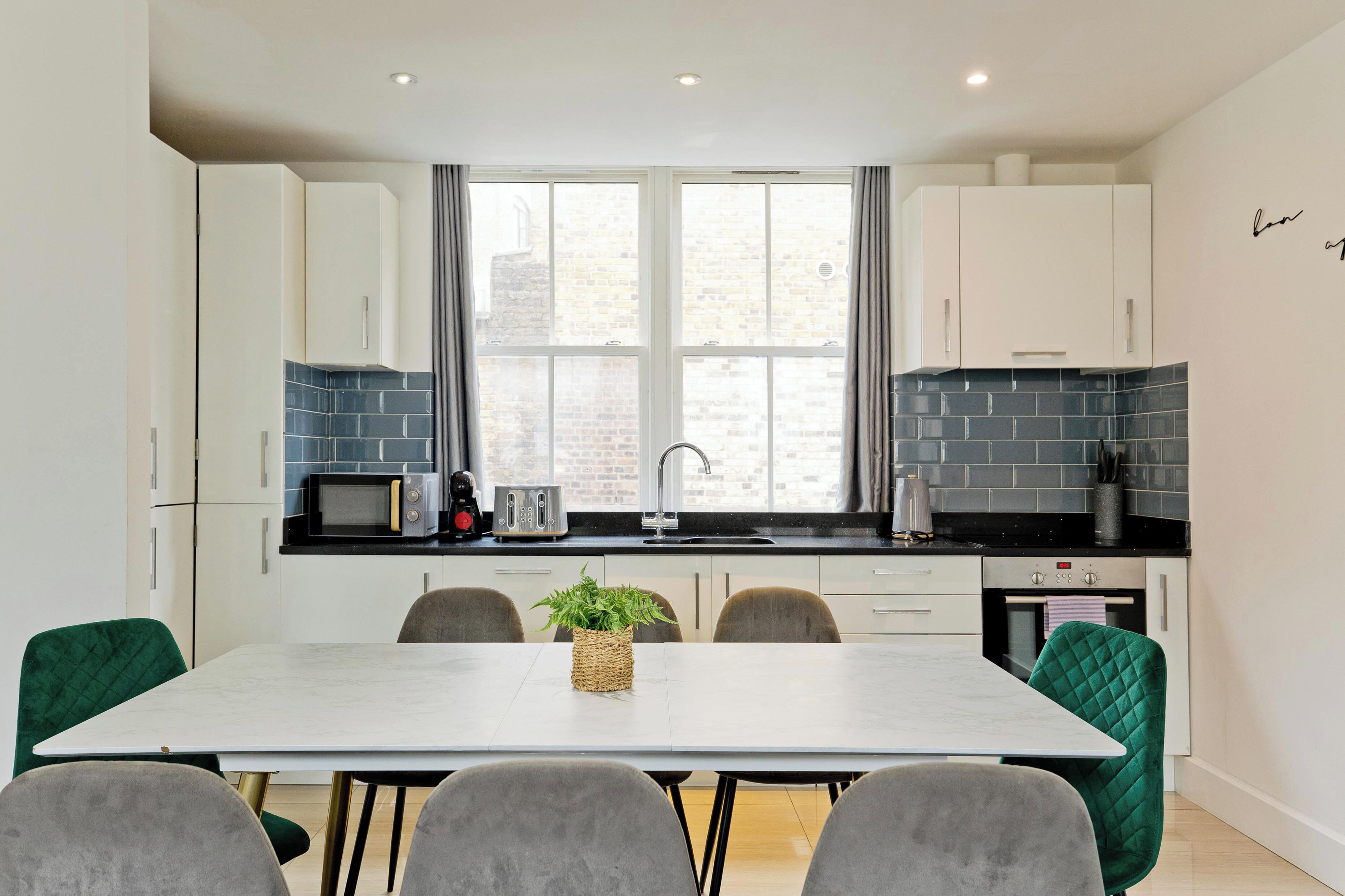 A modern kitchen with white cabinets, a black countertop, and a large window.