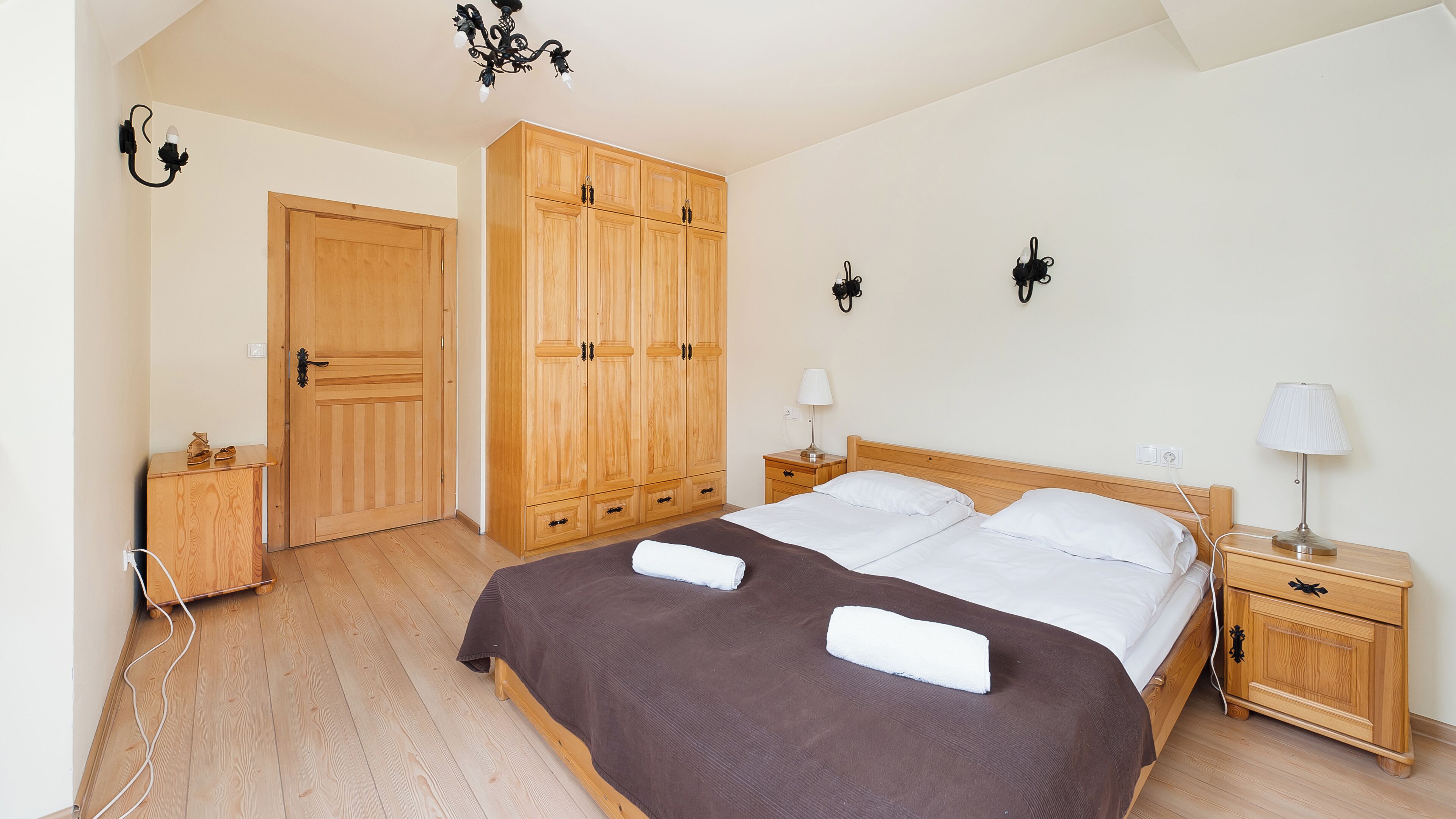 Une chambre à coucher avec un grand lit, une armoire en bois, des tables de chevet et un lustre.