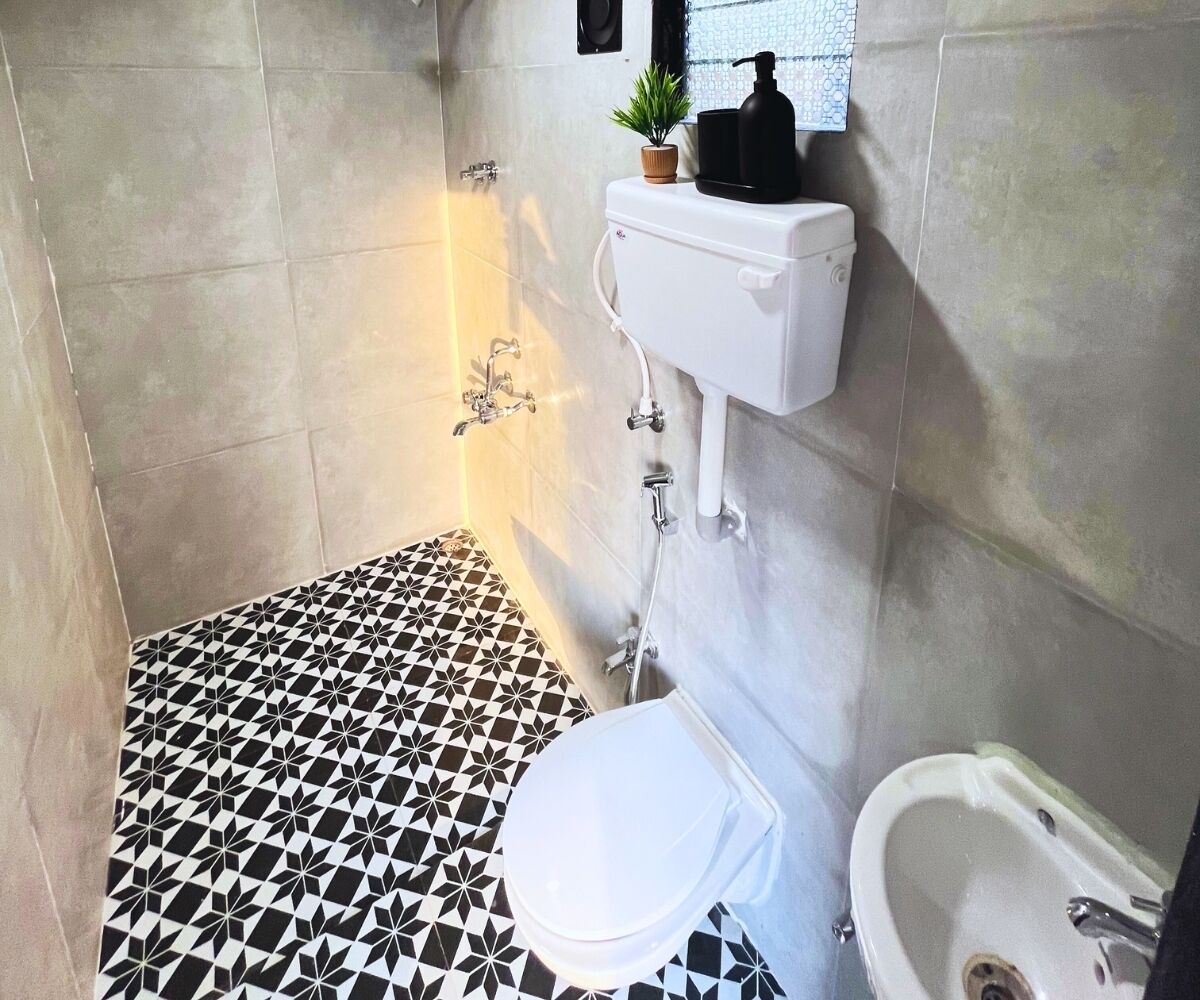 A bathroom with a black and white patterned floor, a toilet, a sink, and a shower area.