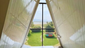 A room with a bed and a view of a garden through a window. - Sizzle Bay Resort (Mawal)