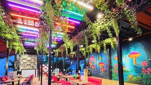 A restaurant with wooden flooring, red and black seating, and a mural of mushrooms. - Sizzle Bay Resort (Mawal)