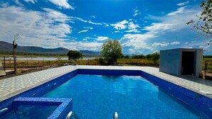 A rectangular swimming pool with blue tiles, surrounded by a paved deck. - Sizzle Bay Resort (Mawal)
