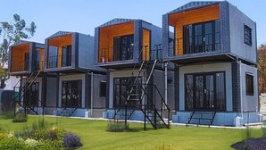 A modern multi-story residential building with a symmetrical design, featuring large windows and a central staircase. - Sizzle Bay Resort (Mawal)