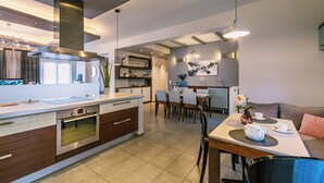 Una cocina moderna con horno integrado, un comedor con mesa y sillas, y una sala de estar con sofá y mesa de centro.