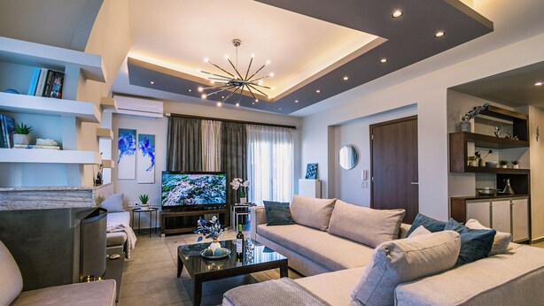 Una sala de estar moderna con sofá, mesa de centro, televisor y estanterías empotradas.