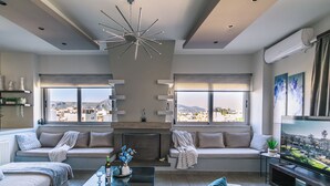 A modern living room with a fireplace, two sofas, a coffee table, and a TV. - ARTica condo 1_2BR with fireplace, near Amoudara & Heraklion. Free Parking (TSALIKAKI-D.MALEVIZIOU)
