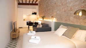 A hotel room with a bed, a sofa, a desk, and a stone wall. - Montgo Loft Apartment (Dénia)