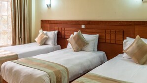 A hotel room with two single beds, each with a wooden headboard and white bedding. - Royal Green Gardens (Nakuru)