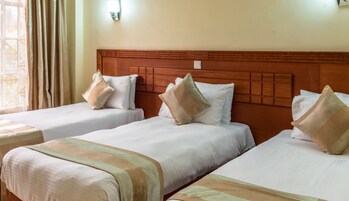 Una habitación de hotel con dos camas individuales, cada una con cabecero de madera y ropa de cama blanca.