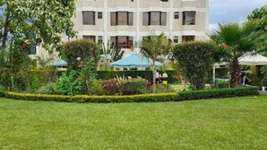 A hotel with a well-maintained garden, outdoor seating, and a multi-story building with balconies. - Royal Green Gardens (Nakuru)