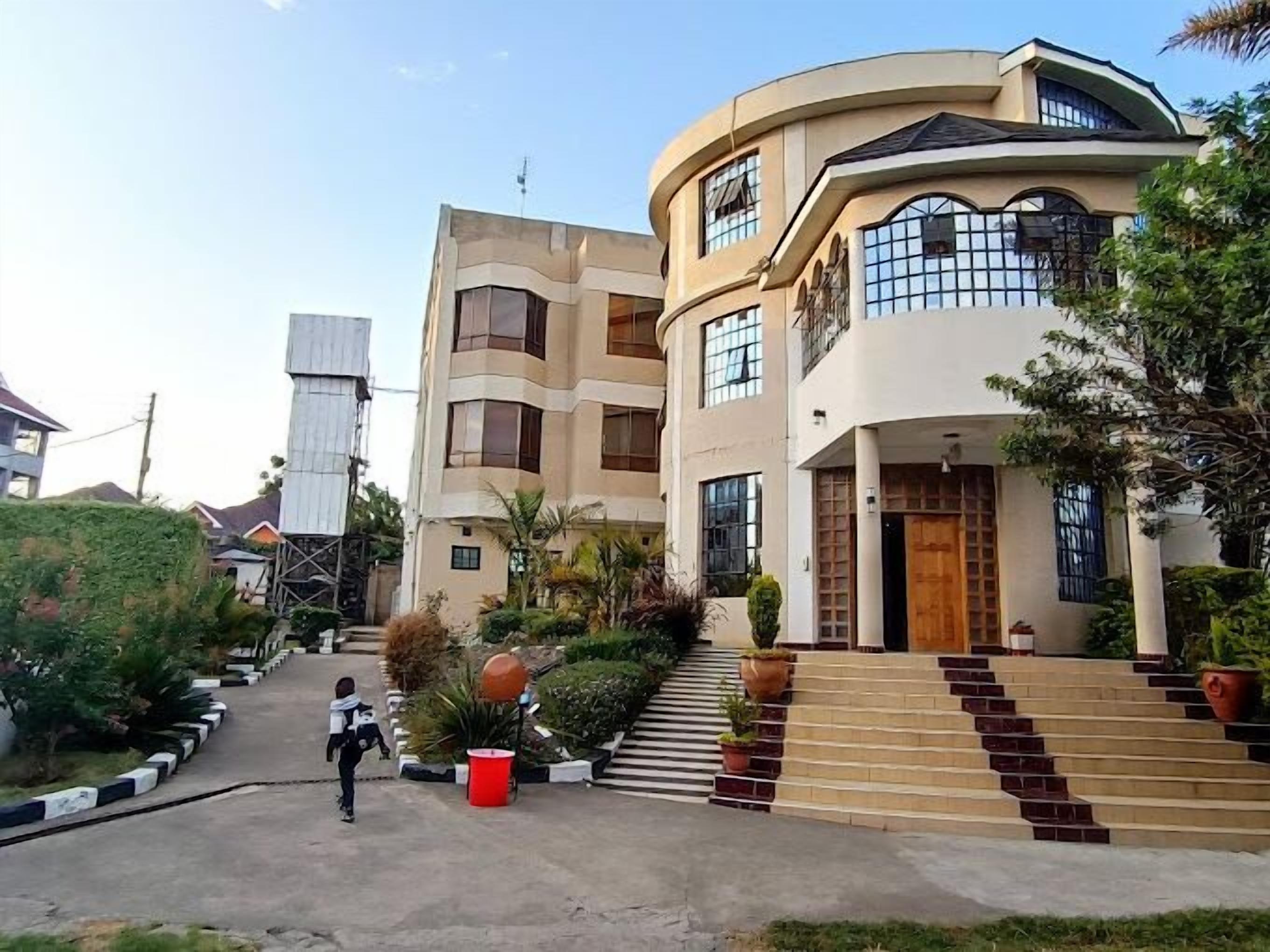 A modern multi-story building with a curved facade, large windows, and a central staircase leading to the entrance.