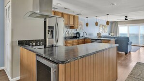 Une cuisine moderne avec des meubles en bois, une hotte en acier inoxydable et un îlot central doté d’un plan de travail foncé.