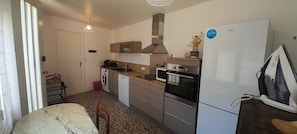 A compact kitchen with a washing machine, oven, microwave, and a refrigerator. - 2 bedroom apartment with terrace- Wifi in the heart of Levroux (Levroux)