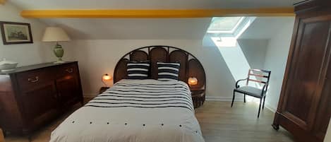 A bedroom with a bed, two bedside lamps, a chair, a dresser, and a picture on the wall.