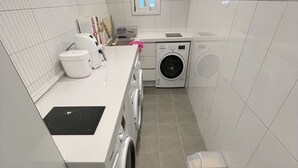 A compact laundry room with a washing machine, dryer, and a small window. - SRR STAY (Gwangmyeong)