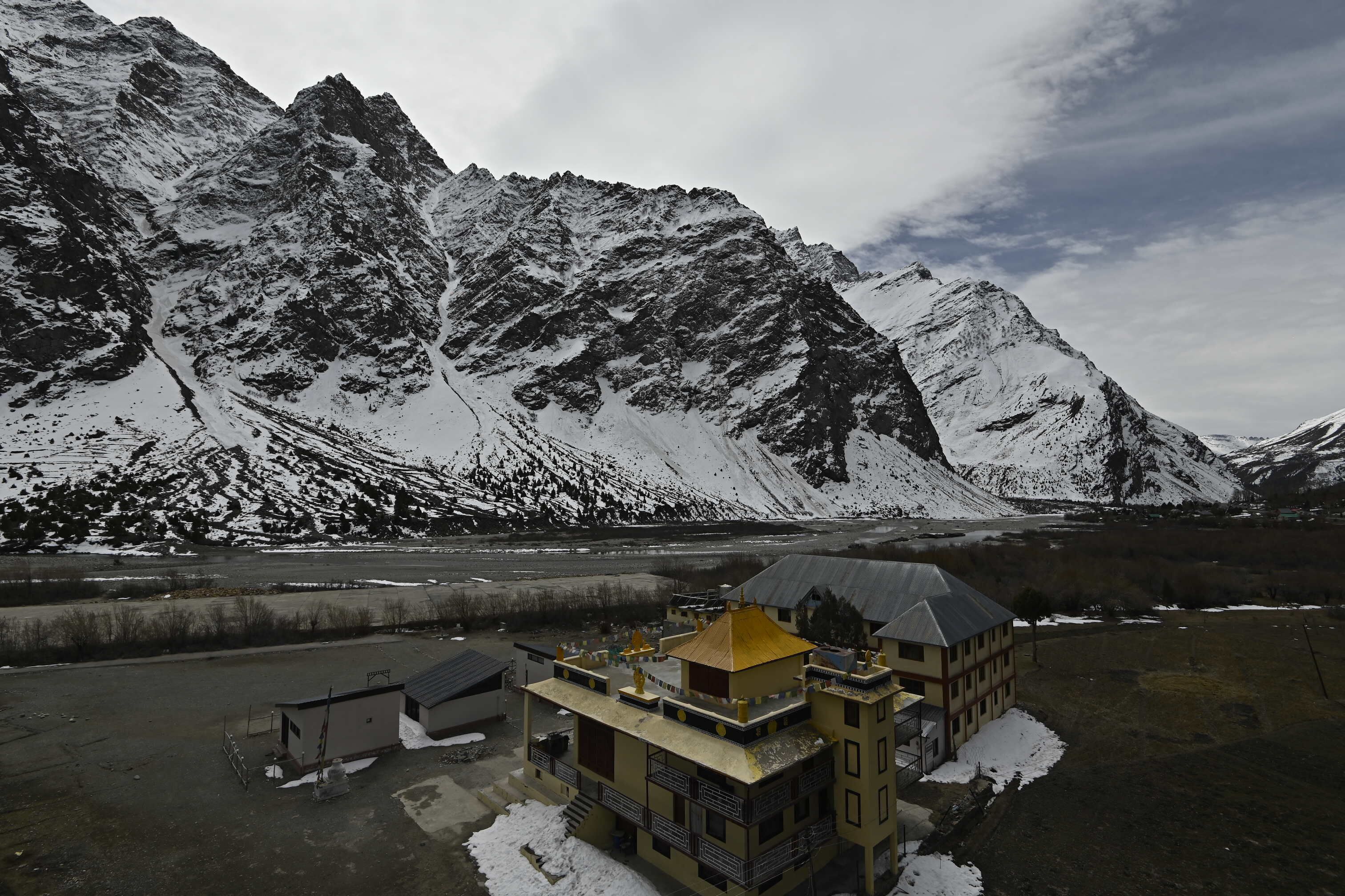 A mountainous landscape with snow-covered peaks and a building with a yellow roof.