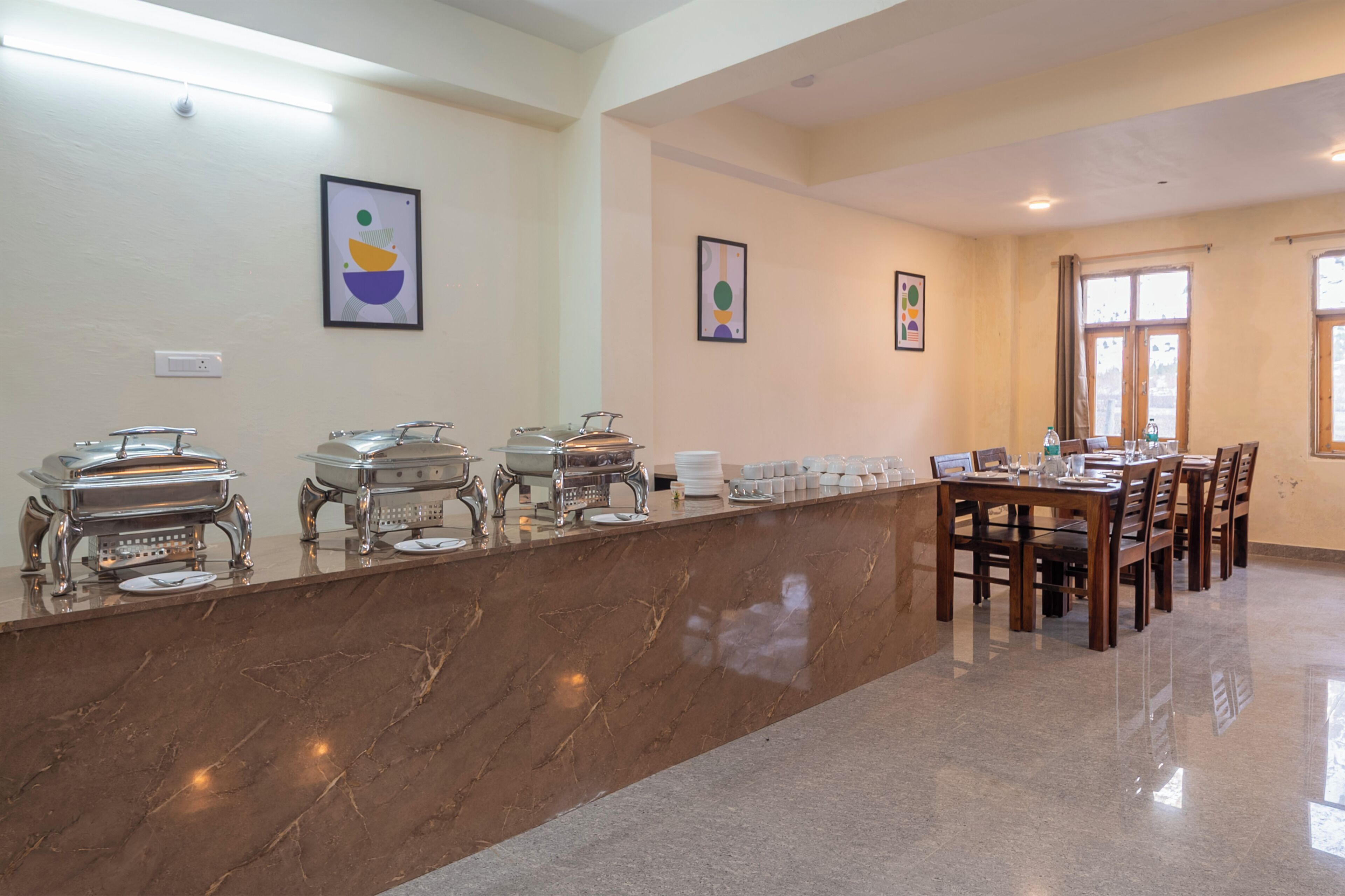 Un buffet avec plusieurs points de service, un long comptoir et un espace repas comprenant des tables et des chaises.