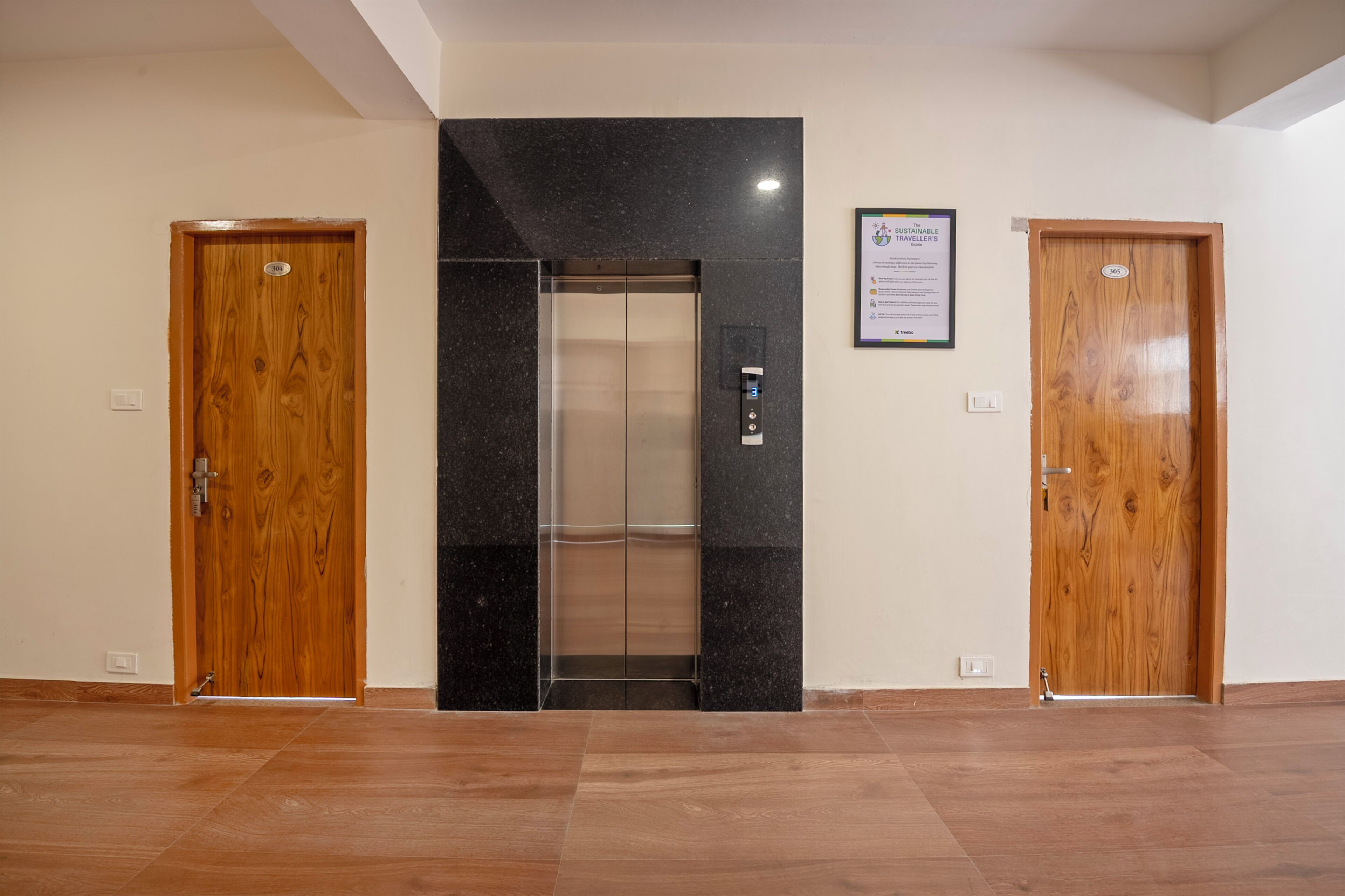 Un pasillo con dos puertas de madera, un ascensor negro y un certificado enmarcado en la pared.
