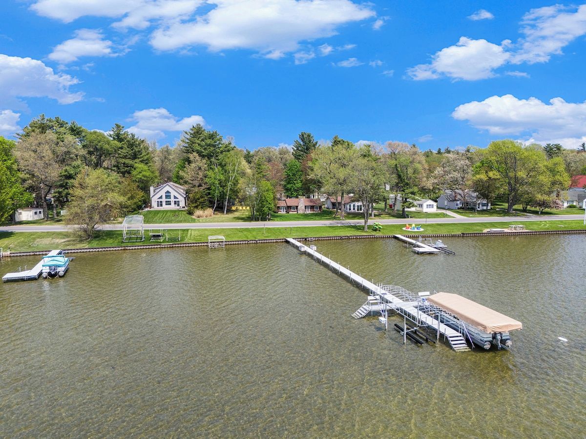 A lake with a dock and a house in the background.