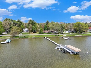 Un lago con un muelle y una casa al fondo.