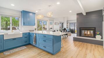 A modern kitchen with blue cabinets, a large island, and a fireplace.