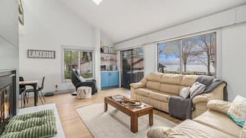 Un salon moderne avec une cheminée, un canapé, une table basse et une vue sur un paysage enneigé, visible à travers de grandes fenêtres.