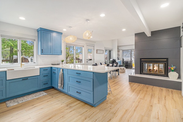 A modern kitchen with blue cabinets, a large island, and a fireplace.
