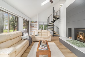 Relax in this stylish living room with a comfortable sofa, coffee table, and fireplace, offering views of the outdoors.