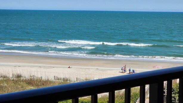 A beach with waves, a sandy shore, and a few people.