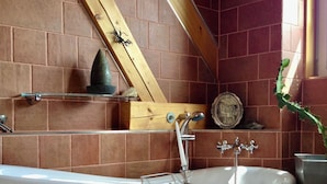 Ein Badezimmer mit freistehender Badewanne, Holzbalken und einer Ziegelwand.