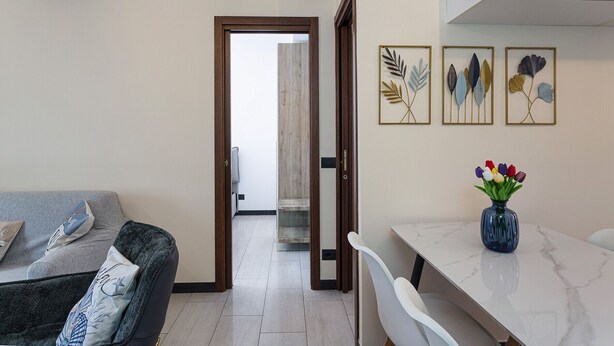 A modern living room with a sofa, a dining table, and a vase of tulips. - Appartamento Centrale con Terrazzo by Wonderful Italy (Santa Margherita Ligure)