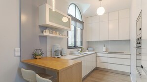 A modern kitchen with white cabinetry, a wooden countertop, and a built-in oven. - Casa Bela Vista (São Gonçalo)