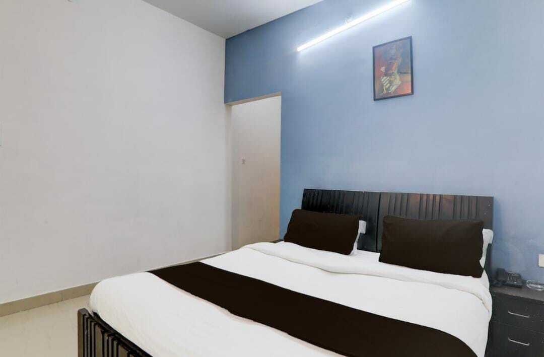 A bedroom with a bed, a nightstand, and a painting on the wall.