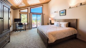 A bedroom with a large bed, a desk, and a computer. There is a window with a view of trees and mountains. - Monthly Lease - Infinity Ridge by Tahoe Getaways - 3BR, Well Travelled Dog Considered. (Truckee)