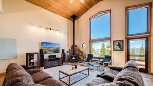 A cozy living room with a stone fireplace, large windows, and comfortable seating. - Monthly Lease - Infinity Ridge by Tahoe Getaways - 3BR, Well Travelled Dog Considered. (Truckee)