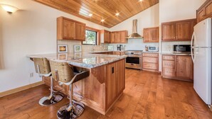 A modern kitchen with wooden cabinets, a central island, bar stools, and built-in appliances. - Monthly Lease - Infinity Ridge by Tahoe Getaways - 3BR, Well Travelled Dog Considered. (Truckee)
