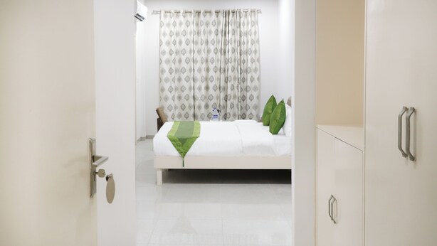 A hotel room with a bed, a bathroom door, and a wardrobe.