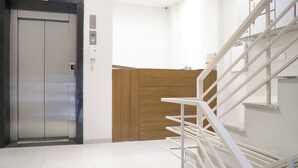 A modern elevator, a wooden panel wall, and a white staircase.