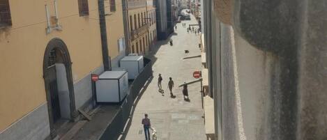 Vistall del carrer amb edificis, una vorera i algunes persones caminant.