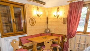 A wooden interior with a wooden table, four chairs, a bench, and a radiator. - Casa Salvaniera (San Vito di Cadore)
