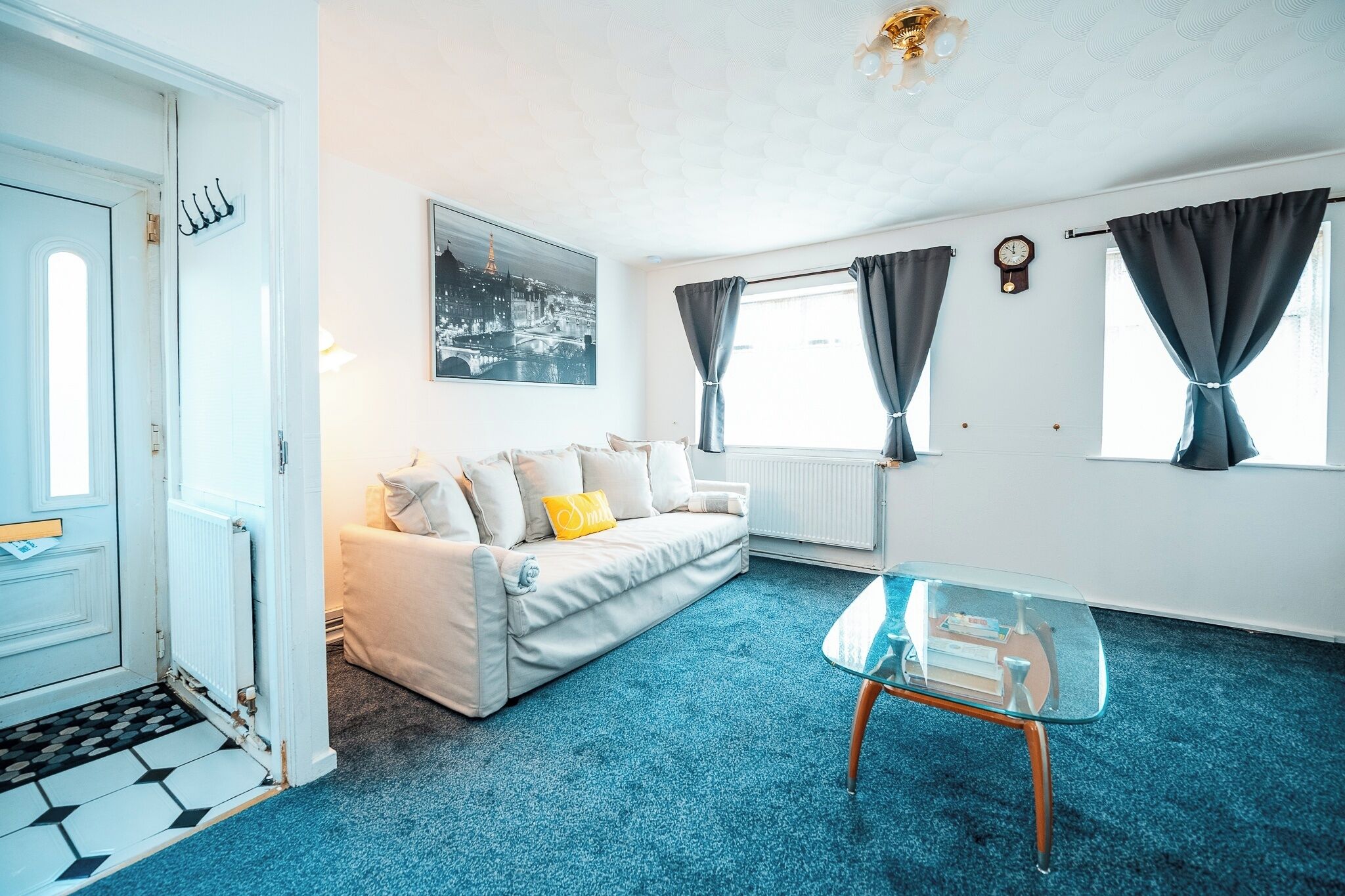 Een kamer met een witte bank, een glazen salontafel en uitzicht op de Eiffeltoren door het raam.