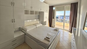 Ein Schlafzimmer mit großem Bett, Einbauschrank und Balkon mit Stadtblick.