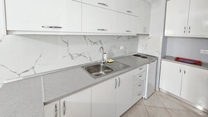 Eine moderne Küche mit weißen Schränken, einer Marmor-Spritzschutzwand und einem Edelstahl-Spülbecken.