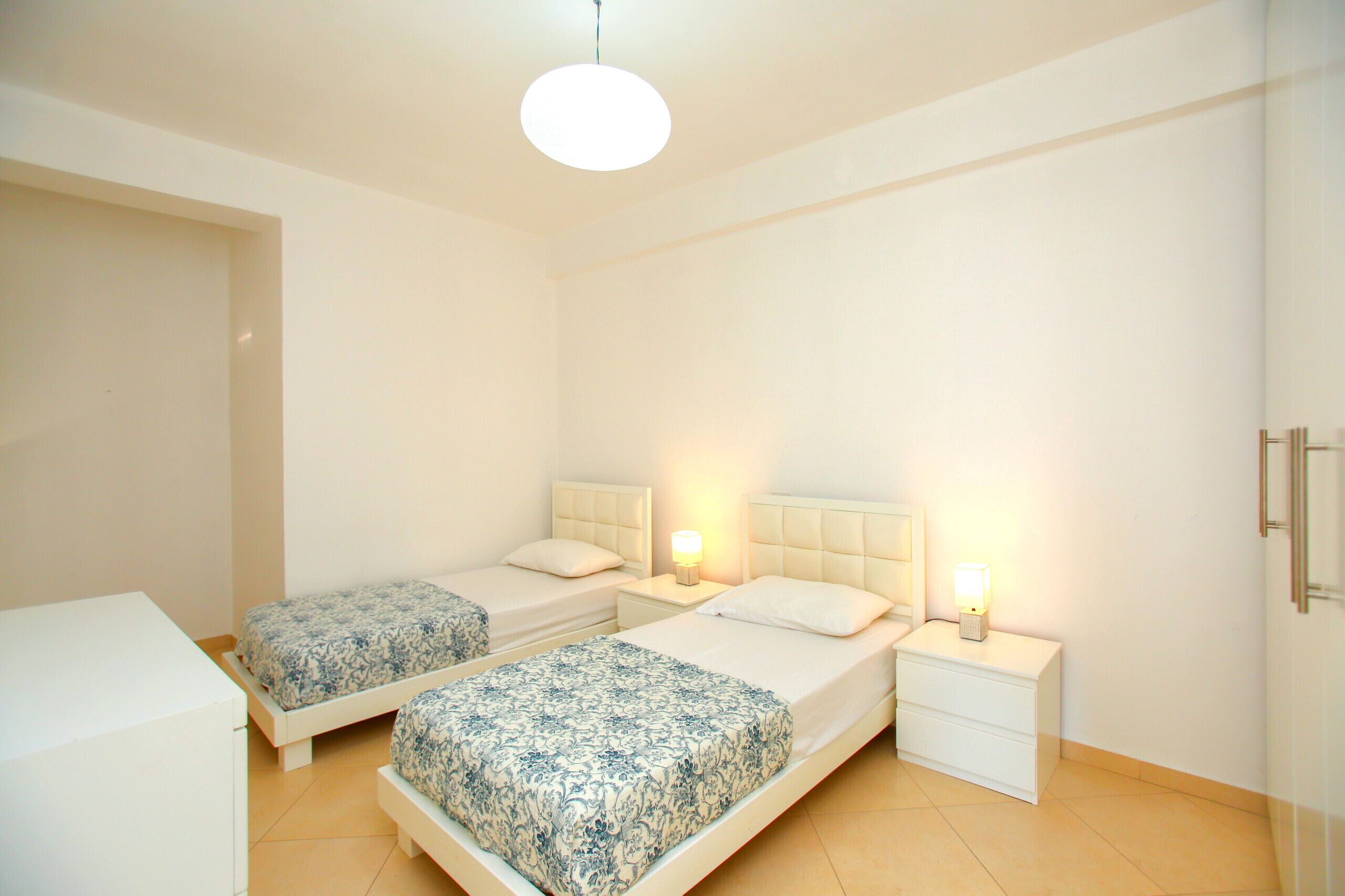 Une chambre avec deux lits, une table de chevet, une commode et une armoire.