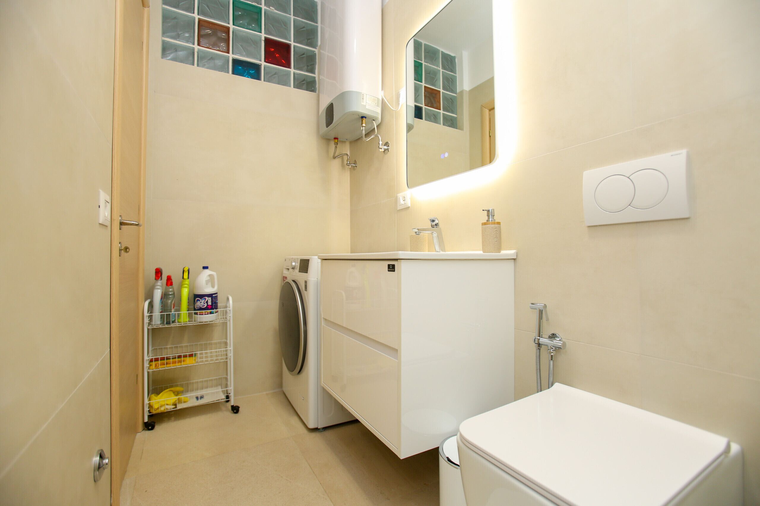 A compact bathroom with a washing machine, a sink, and a toilet.