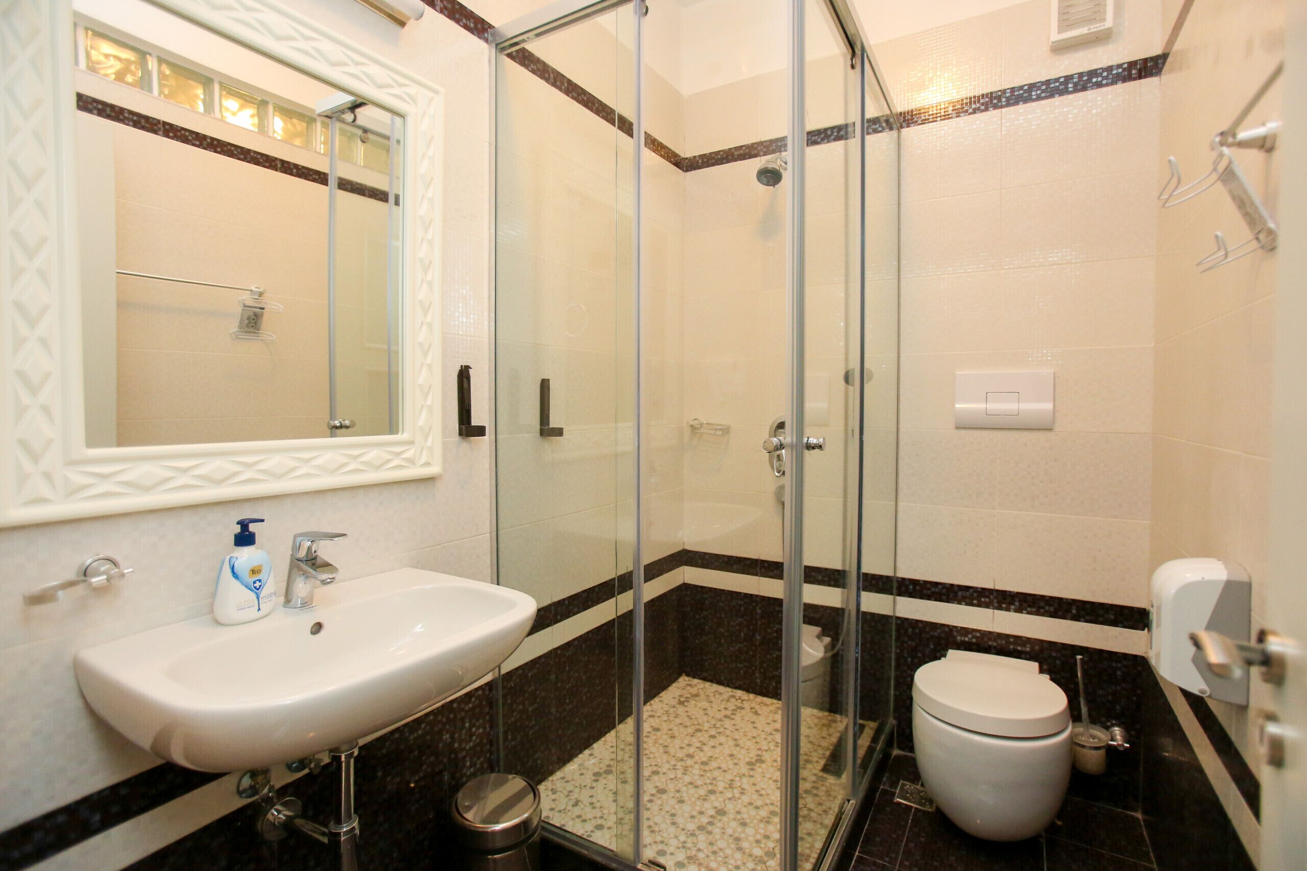 A bathroom with a glass-enclosed shower, a white sink, and a toilet.