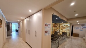 Een hal met een zithoek, een stenen muur en een glazen scheidingswand.