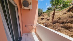 A balcony with a metal drying rack, a window with a closed blind, and an air conditioning unit mounted on the wall. - Teo's Deluxe Studios - Balcony Triple Studio (Vlorë)